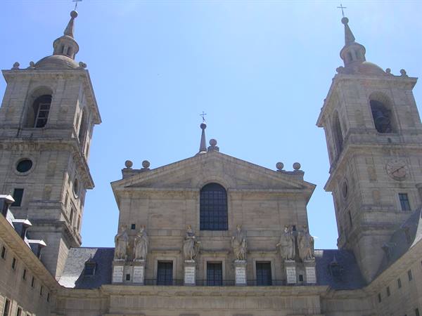 Granite facade of El Escorial basilica, two bell towers under a blue sky