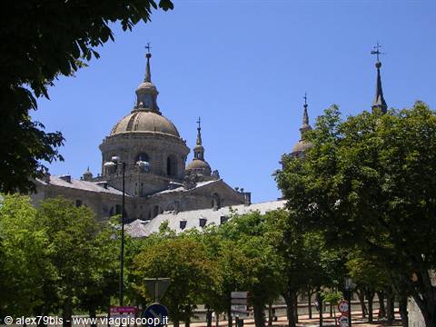 The granite domes of El Escorial monastery rise above the green trees