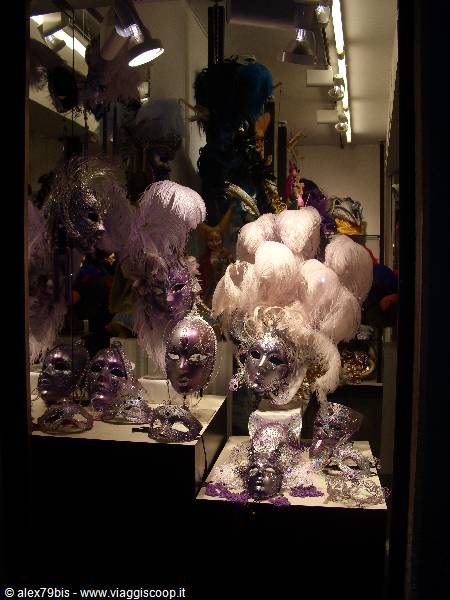 Shop window with silver Venetian masks and white purple feathers