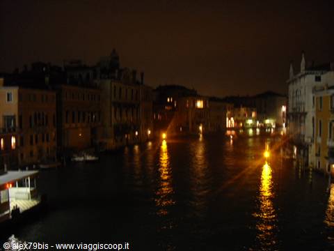 Grand Canal in Venice at night, yellow lights reflected on dark water between buildings