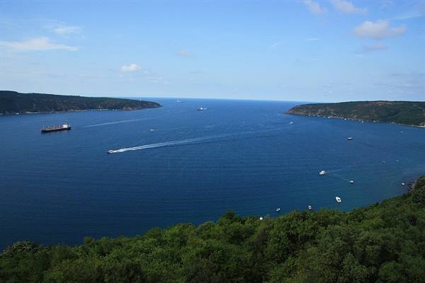Ships and ferries cross the green strait between wooded hills