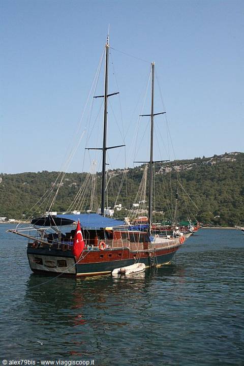 Wooden gulet with Turkish flag anchored in a green bay