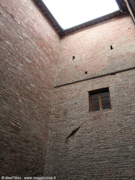 Inner courtyard with red brick walls, wooden window, daylight from open sky