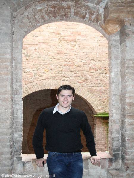 Young man in black sweater under an ancient brick archway, natural light