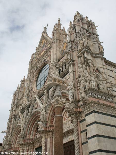 Siena Cathedral facade with the she-wolf column, white and red marble statues