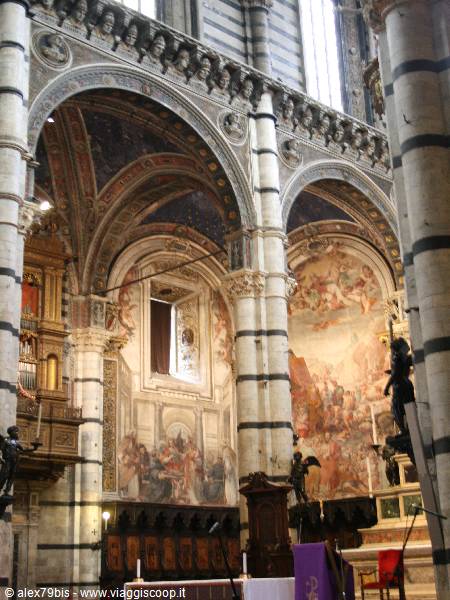 Inside Siena Cathedral, black and white striped columns, frescoes and altar