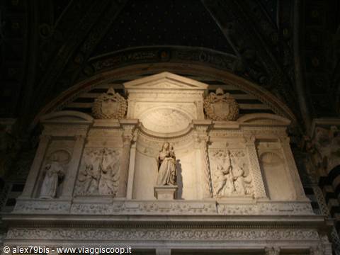 Marble monument with Madonna and Child and statues, lit inside Siena cathedral