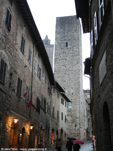 San Gimignano, street with umbrellas beneath medieval stone towers
