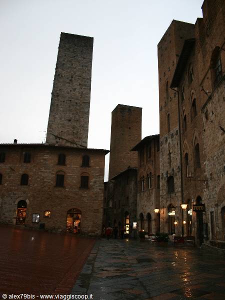Piazza della Cisterna in San Gimignano, medieval stone towers under dim light