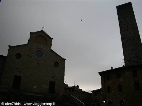 Medieval church and stone tower in San Gimignano under gray sky