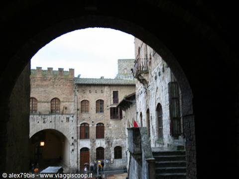 Medieval stone houses seen through a dark archway in San Gimignano