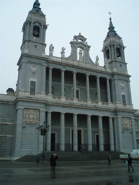 Almudena Cathedral in Madrid, grey neoclassical facade with twin towers under overcast sky