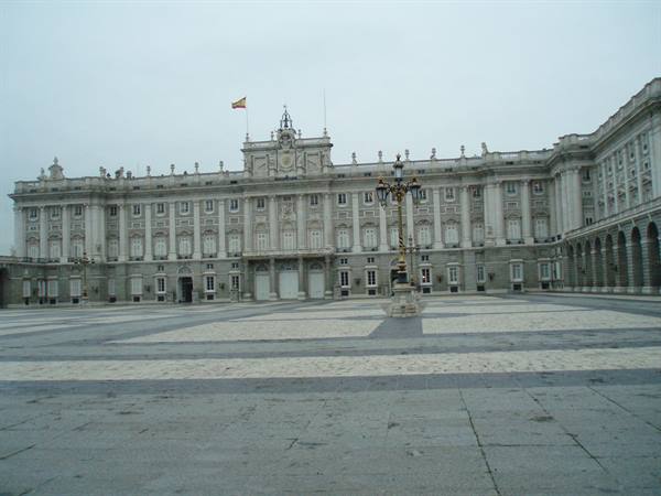 Royal Palace of Madrid, stone facade under gray sky, empty square with lamppost