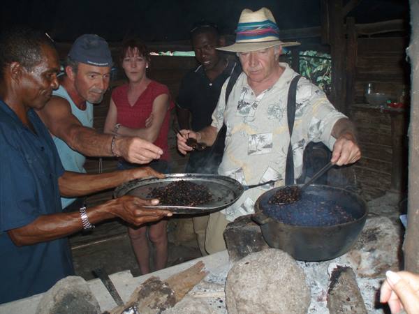 Tourist tastes roasted coffee from black pot over coals with locals