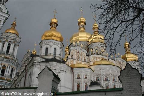 The golden domes of Kyiv Lavra among bare branches under a grey sky