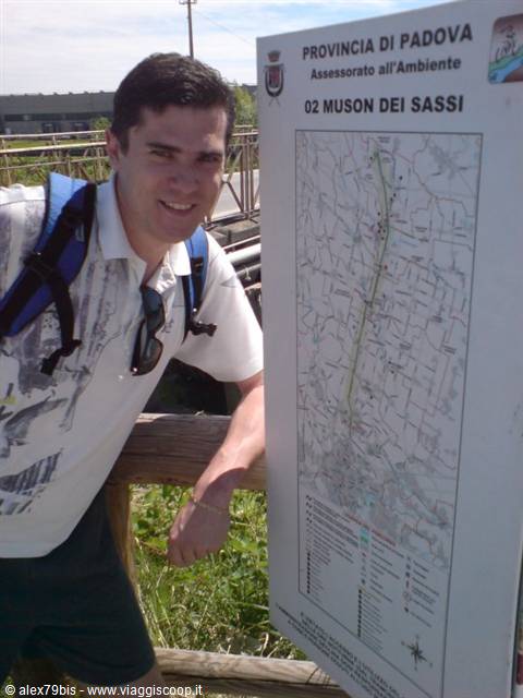 Hiker with backpack next to the Muson dei Sassi trail map sign in Padua