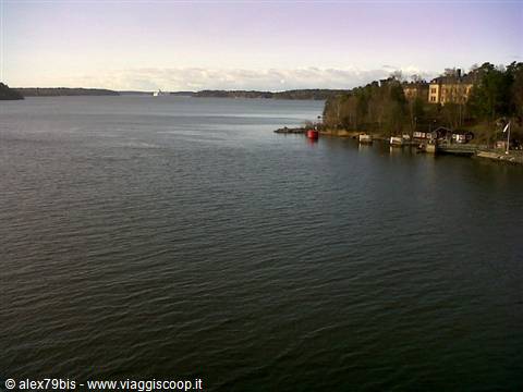 Bay with yellow houses and moored boats along Stockholm's wooded shore