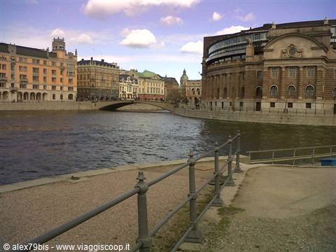 Stockholm's Riksdag in dark brick by the water, historic buildings and a bridge