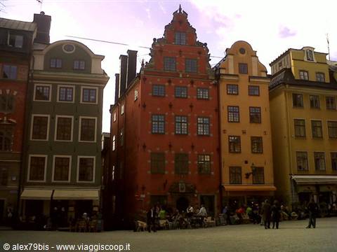 Colorful houses on Stortorget square in Stockholm, people walking under cloudy sky