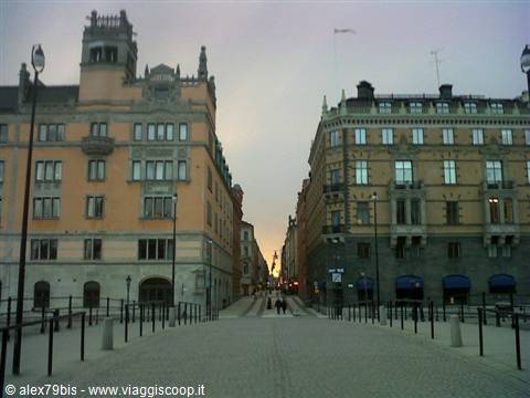 Stockholm: bridge toward Gamla Stan between historic buildings, few people at dusk