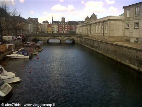 Boats moored along the canal, stone bridge and colorful buildings in Copenhagen