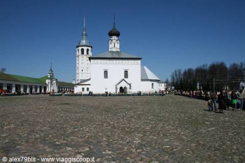 White church with black onion dome on cobbled square in Suzdal