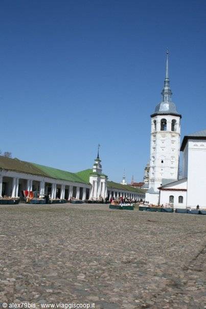White bell tower and market arcades in Suzdal under a blue sky