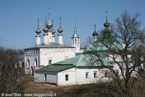 White church with silver onion domes and green roof amid bare trees