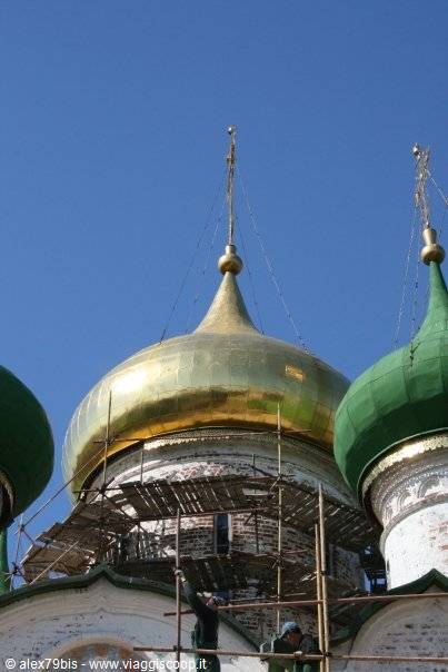 Workers on scaffolding restore the golden and green domes of an Orthodox church