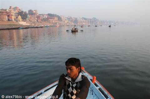Boy rowing a wooden boat on the Ganges in misty Varanasi at dawn