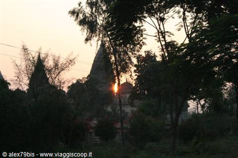 Stone temple spires among trees, orange sun glowing through the branches