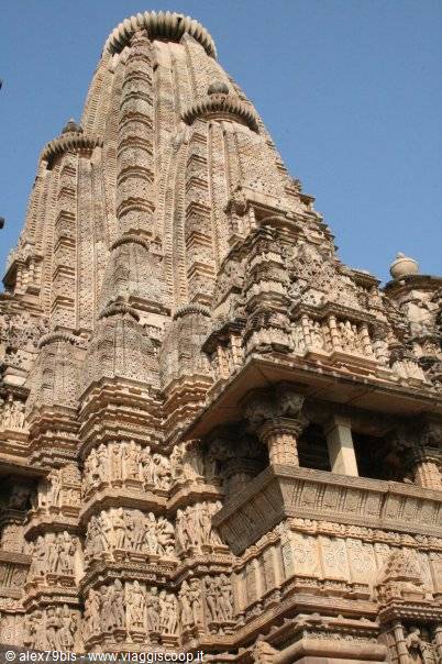 Khajuraho sandstone temple, carved sculptures on the towering shikhara against blue sky