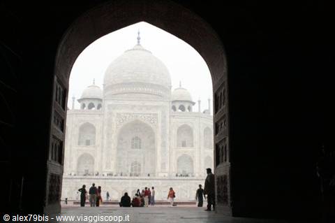The Taj Mahal framed by a dark arch, visitors in the haze