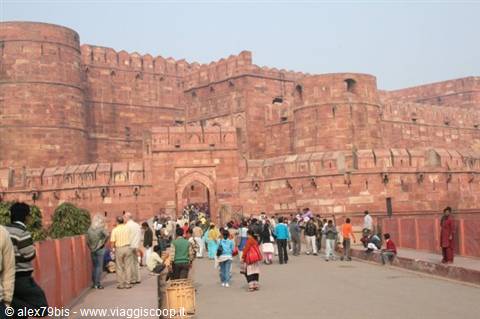 Tourists walk toward the massive red sandstone entrance of Agra Fort