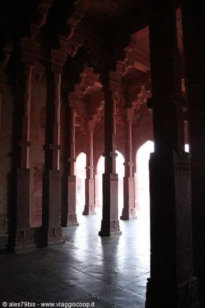Red sandstone columns in Fatehpur Sikri hall, light filtering through arches