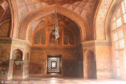 Mughal tomb interior with floral painted vaults, hanging lamp, light through latticed windows