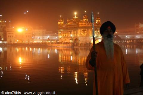 Sikh guard with spear before the illuminated Golden Temple, Amritsar