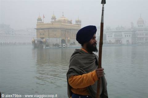 Sikh guard with spear and blue turban before the Golden Temple in Amritsar fog