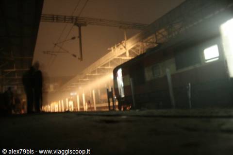 Blurred traveler on station platform, train parked under warm night lights