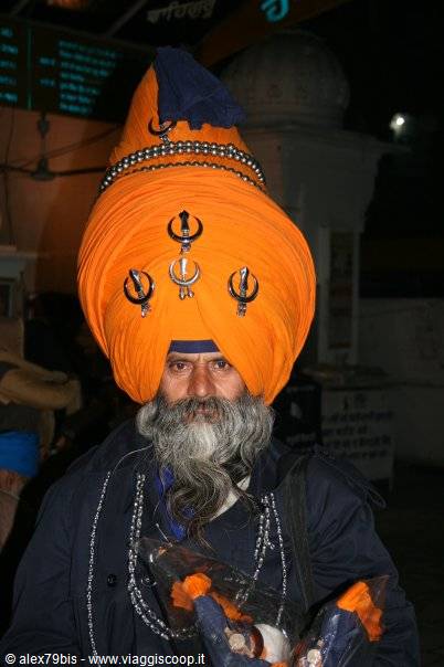 Sikh man wearing huge orange turban and grey beard, at night