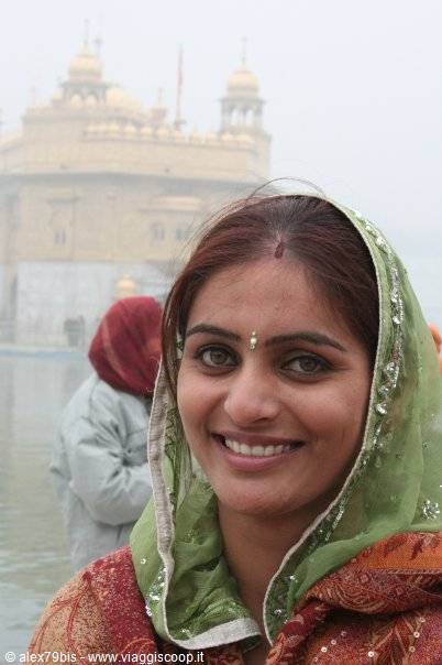 Smiling woman in green veil before the Golden Temple in fog, Amritsar