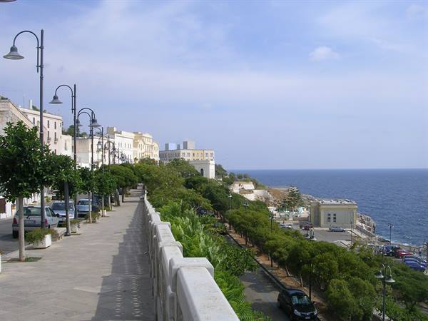 Seafront promenade in Santa Cesarea Terme with stone parapet, lampposts and trees