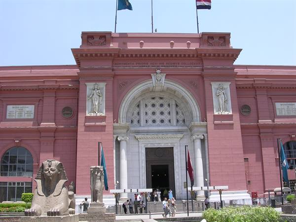 The Egyptian Museum in Cairo: pink facade, granite sphinx, tourists at the entrance