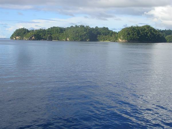 Green islands with sandy beach rise from calm sea under clouds
