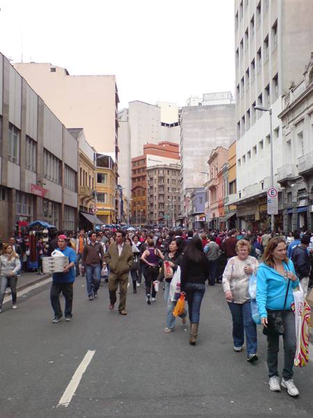 Crowd of pedestrians walking along busy downtown street between tall buildings