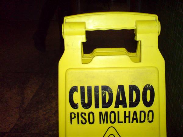 Yellow plastic caution sign reading Cuidado Piso Molhado, wet floor