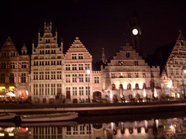 Illuminated medieval guildhouses along the Graslei canal in Ghent, reflected in the water