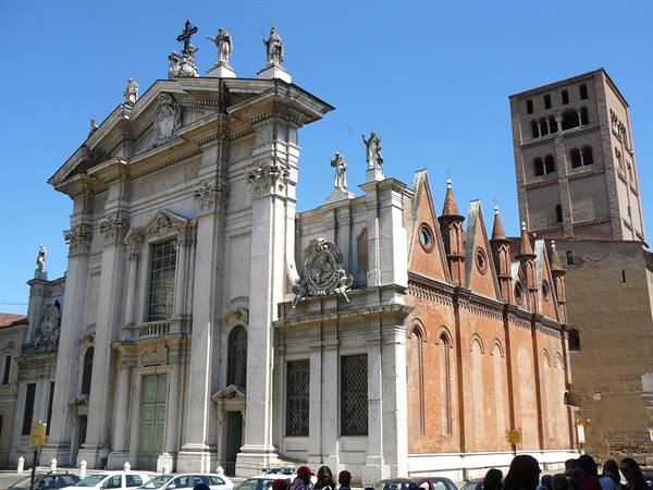 Marble facade of Mantua Cathedral with brick spires and bell tower