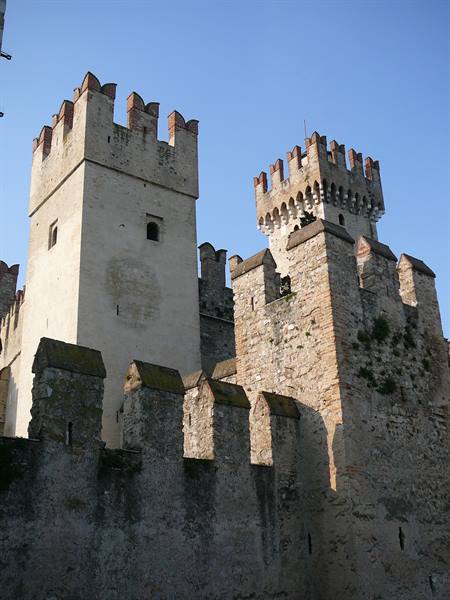 Crenellated stone towers of a medieval castle against clear blue sky