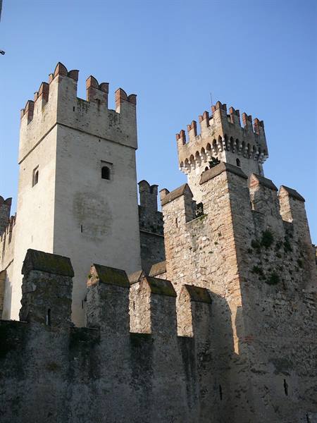 Crenellated stone towers of Scaligero Castle in Sirmione against blue sky